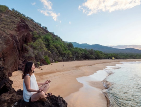 Femme qui médite sur un rocher sur la plage