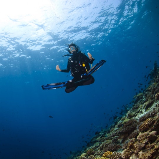 Femme qui médite en tenue de plongée sous l'eau