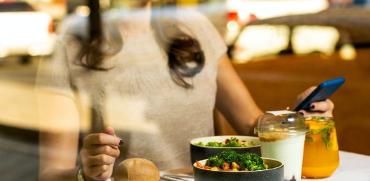 Femme qui mange en regardant son téléphone